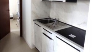A modern kitchen with white cabinets, a black countertop, and a stainless steel sink. - Minimalist Apartment in a Quiet Area - Beahost (San Michele al Tagliamento)