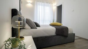 Ein modernes Schlafzimmer mit Bett, Nachttischlampe und einer Topfpflanze.