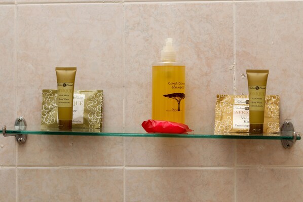 A bathroom shelf with three toiletry items: a body wash, a shampoo, and a lotion.