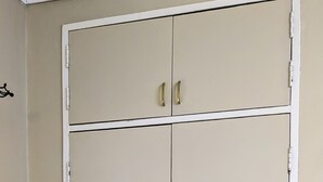 Une armoire fermée à deux portes, avec une petite poubelle placée à côté.