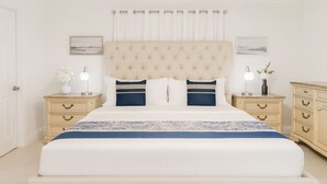 A bedroom with a large bed, two nightstands, a ceiling fan, and a window with curtains.