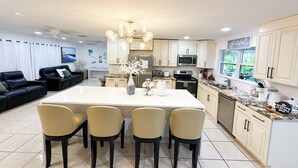 A modern kitchen with a central island, white cabinets, and a dining area with four chairs.