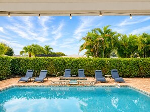 A swimming pool with lounge chairs and palm trees in the background.