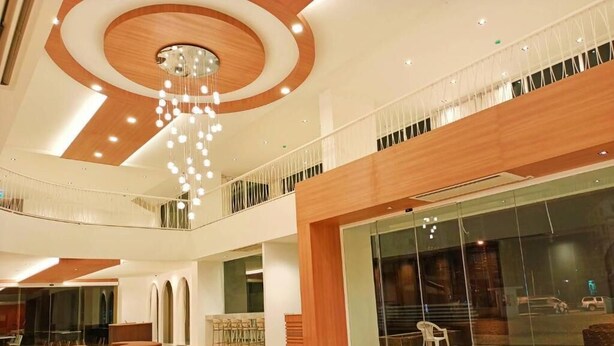 A modern lobby with a central seating area, a glass facade, and a wooden ceiling design. - M CASA HOTEL PATTAYA (Pattaya)