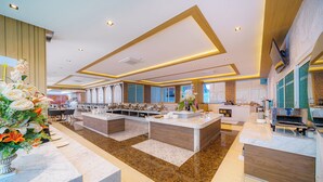 A spacious hotel lobby with a central island, seating areas, and a large window providing natural light. - M CASA HOTEL PATTAYA (Pattaya)