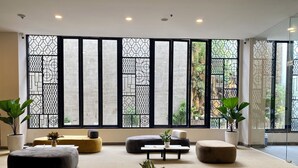 Een moderne lounge met grote ramen, zachte zitplaatsen en potplanten.