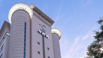 A modern hotel with two cylindrical towers, a prominent sign, and a clear sky.