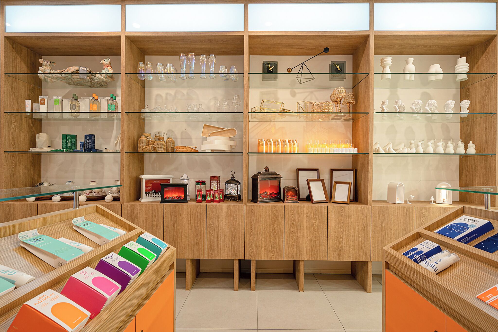 Un magasin avec des étagères en bois où sont exposés divers produits, comme des bougies, des articles en verre et des objets de décoration.