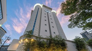 A tall, modern building with a prominent vertical feature and a clock at the top. - Anook Hotel Daejeon Yongjeon Ⅱ (Daejeon)