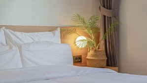 A neatly made bed with white linens, a bedside lamp, and a potted plant on a wooden nightstand. - Anook Hotel Daejeon Yongjeon Ⅱ (Daejeon)