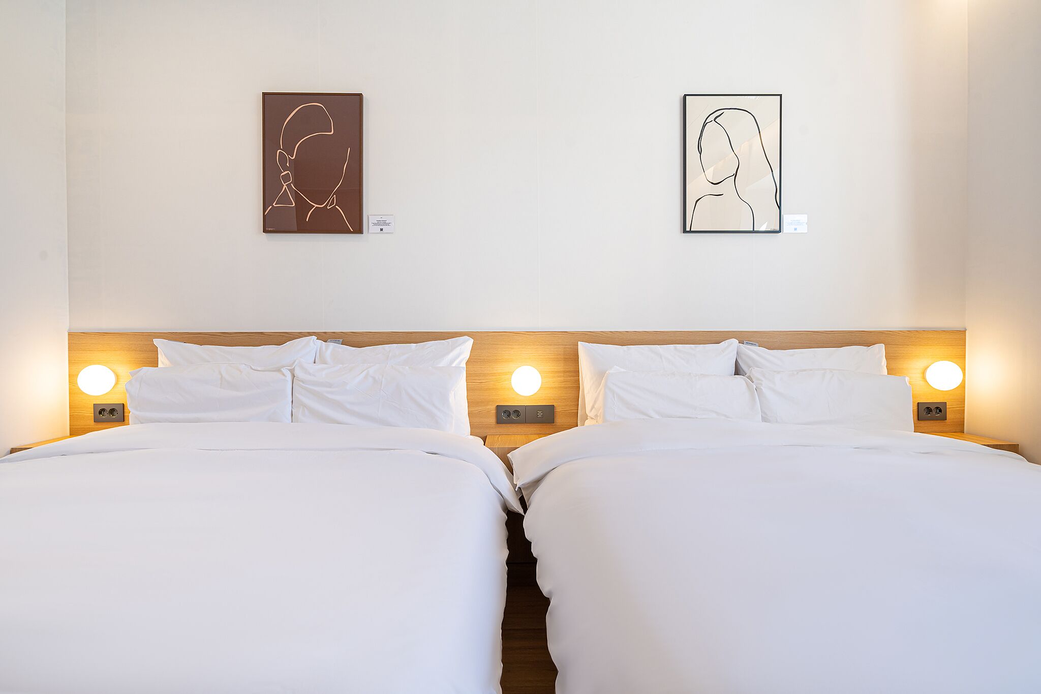 Una cama doble con sábanas blancas y dos lámparas de noche.