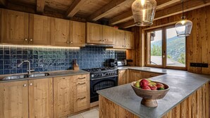 Una cocina con armarios de madera, salpicadero de azulejos, estufa y un amplio ventanal con vistas a la montaña.