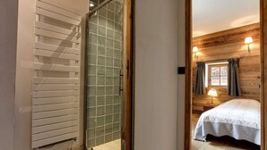 Ein Schlafzimmer mit einem Bett, einer Holzwand, einem Fenster mit Vorhängen und einem Nachttisch mit Lampe.