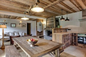 A rustic kitchen with a wooden table, a stone fireplace, and hanging pendant lights. - Family Apart | 360View | Nature | Quiet |Fireplace (Les Houches)