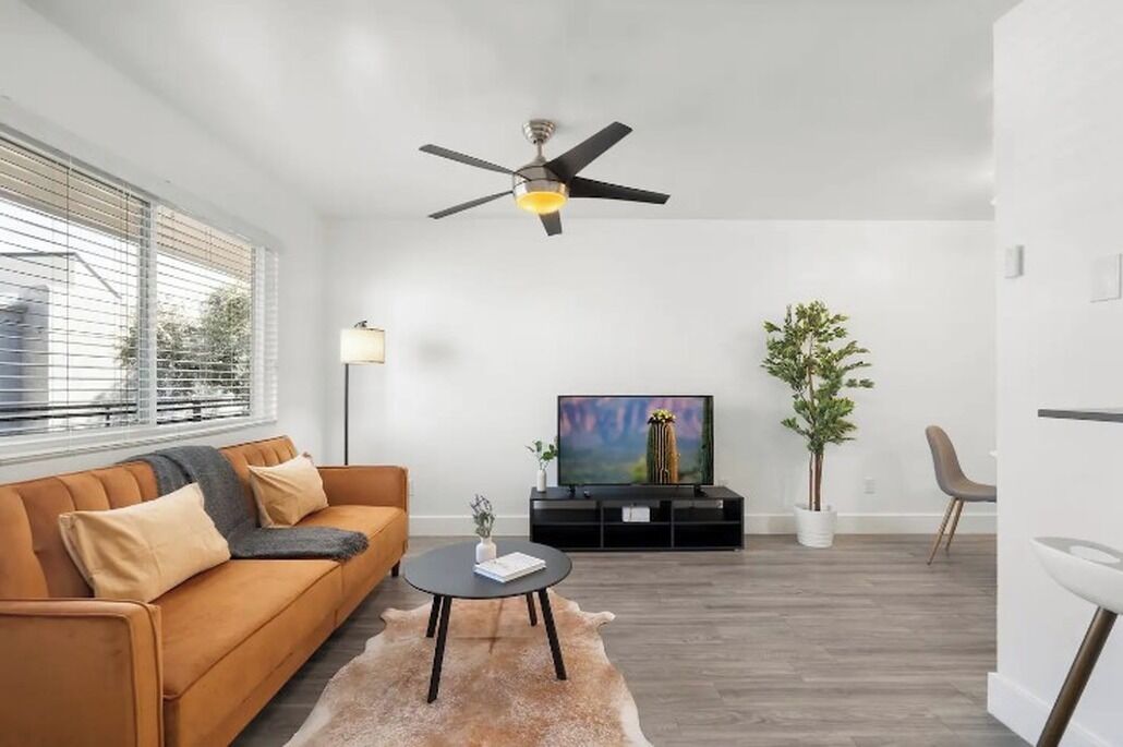 A modern living room with a sofa, a coffee table, a TV, and a ceiling fan.
