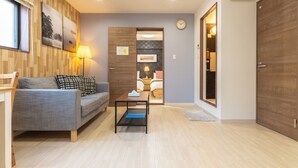 A modern living room with a sofa, coffee table, and a wooden wall with artwork. - VALUE NAMBA SOUTH  (Osaka)