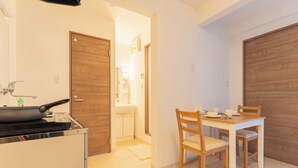 A compact kitchen with a stove, sink, and wooden dining table with chairs. - VALUE NAMBA SOUTH  (Osaka)