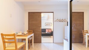 A modern room with a wooden dining table, chairs, and a sofa in the background. - VALUE NAMBA SOUTH  (Osaka)
