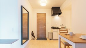 A compact kitchen with a wooden door, a small countertop, and a dining area with a table and chairs. - VALUE NAMBA SOUTH  (Osaka)