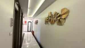 A hallway with a modern design, featuring a marble floor and decorative wall art. - Capital O 1194 Bee Hotel (Nha Trang)