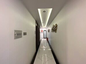 Un couloir avec un panneau « interdiction de fumer », un extincteur et une porte au fond.
