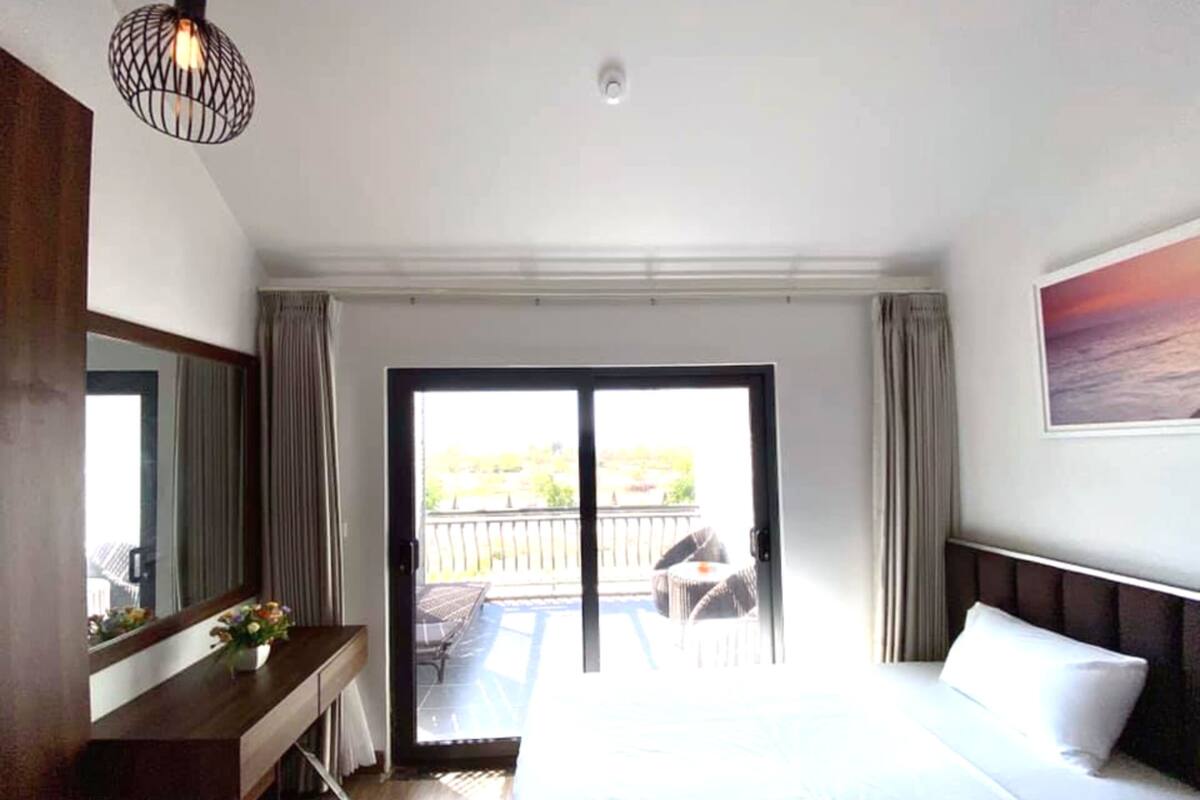 Een hotelkamer met een bed, een bureau, een stoel en een balkon met uitzicht.