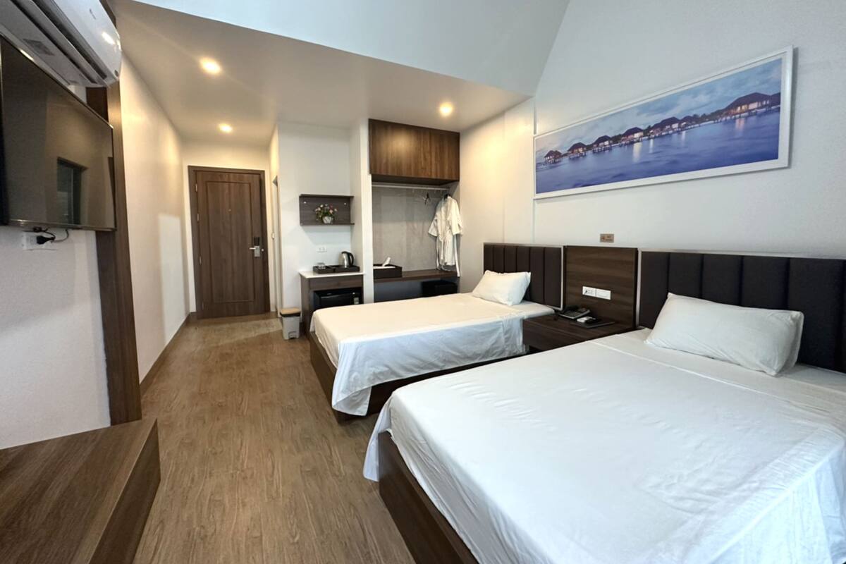 Een hotelkamer met twee éénpersoonsbedden, een bureau, een stoel, een klein tafeltje en een televisie.