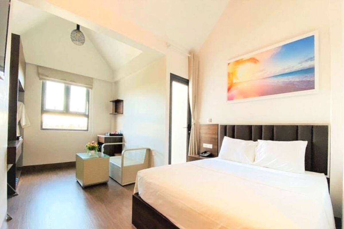 Een hotelkamer met een groot bed, een bureau, een stoel en een raam.