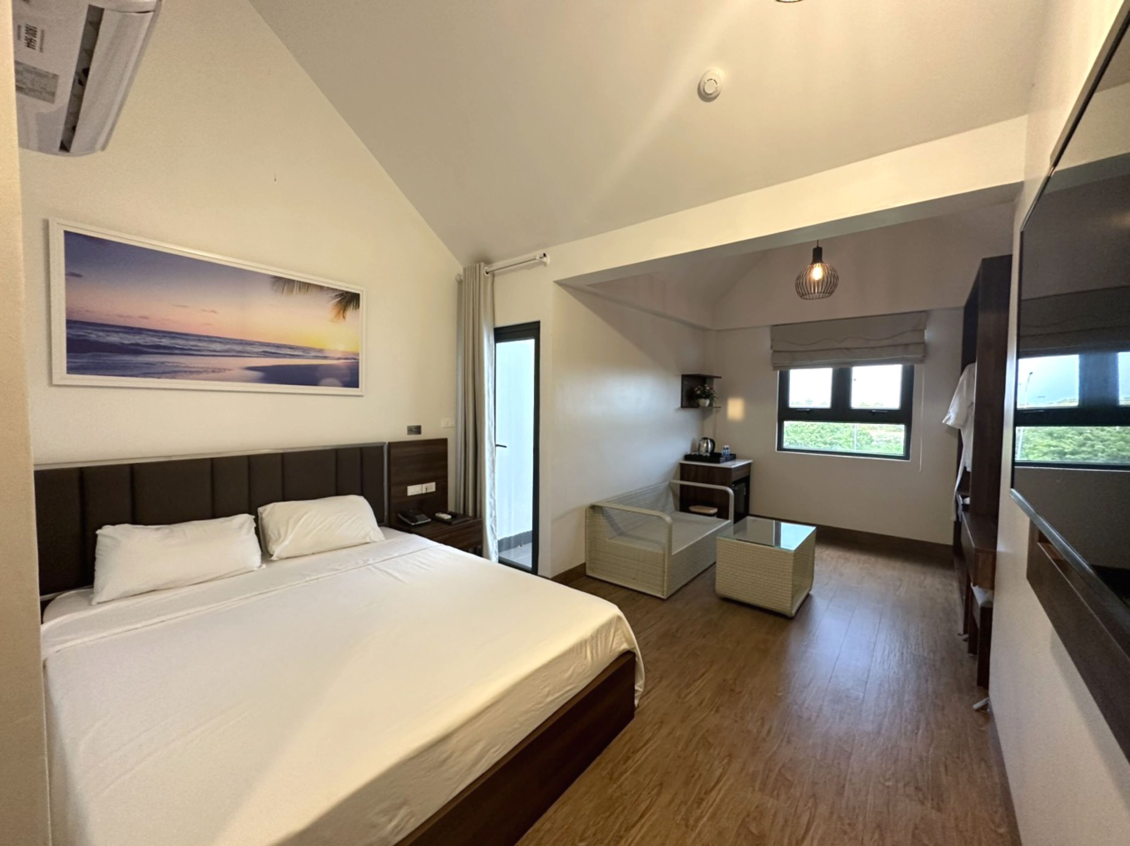 Una habitación de hotel moderna con una cama grande, un escritorio, una silla y una ventana con vistas.