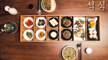 A wooden dining table with various dishes arranged in a traditional Korean style.