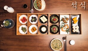 A wooden dining table with various dishes arranged in a traditional Korean style. - Denbasta Ryokan Gyeong-ju (Gyeongju)