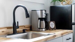 A modern kitchen with a stainless steel sink, a coffee maker, and a black refrigerator. - Hidden Cottage, mins to Main St, Sleeps 4! (Fredericksburg)