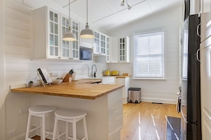 A kitchen with white cabinets, a wooden island with stools, pendant lights, and a black refrigerator. - Hatton Ville Fireplace/Village 5 Minutes/Gardens (Leura)