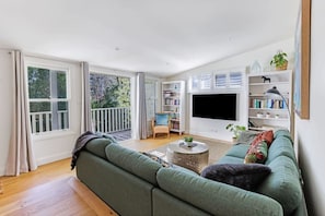 A spacious living room with a large green sofa, a coffee table, a bookshelf, and a TV. - Hatton Ville Fireplace/Village 5 Minutes/Gardens (Leura)