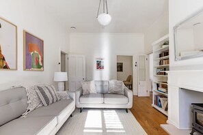 A modern living room with a grey sofa, a white armchair, and a bookshelf. - Hatton Ville Fireplace/Village 5 Minutes/Gardens (Leura)