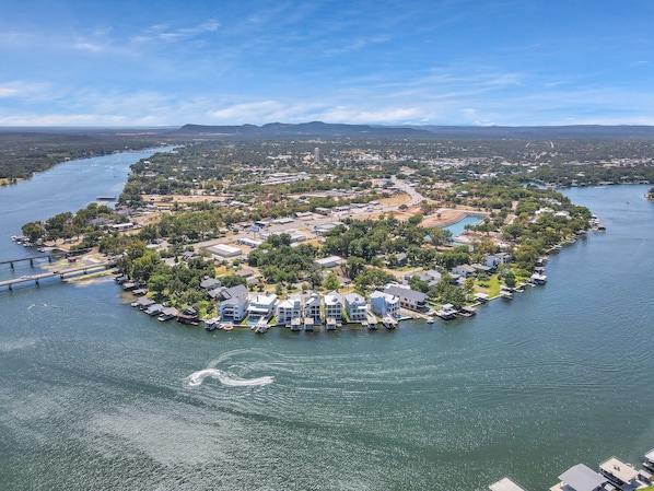 An aerial view of a residential area with houses, a dock, and a bridge across a river.