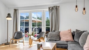 Ein modernes Wohnzimmer mit einer Couch, zwei Sesseln, einem Couchtisch und einer Lampe.