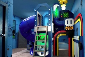 A room with a blue spiral slide, a green ladder, and a caution sign indicating high voltage. - Vor5604aa: 5 Bed, Cartoon Lab, Pool (Orlando)
