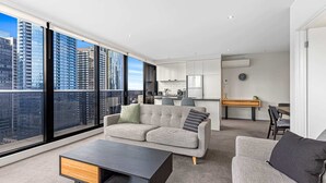 Ein modernes Apartment mit großem Fenster, einer Couch, einem Couchtisch und einer Küchenzeile.