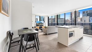 Eine moderne Wohnung mit Essbereich, einer Küchenzeile und großen Fenstern mit Blick auf die Stadt.