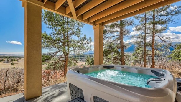 Een hottub onder een pergola, met een bergachtig landschap op de achtergrond.