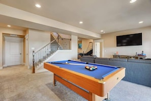A pool table in a living room with a staircase and a flat-screen TV on the wall. - Stargazer Paradise! Hot Tub, Gym & Man Cave (Monument)