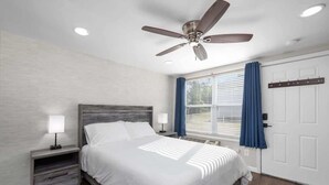 A bedroom with a bed, nightstands, a ceiling fan, a window with curtains, and a coat rack. - Downtown Kimmswick Studio~Renovated~Prime Location (Imperial)