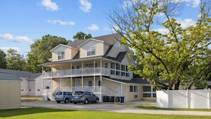 A two-story house with a balcony, a covered porch, and a driveway with two cars parked. - Downtown Kimmswick Studio~Renovated~Prime Location (Imperial)