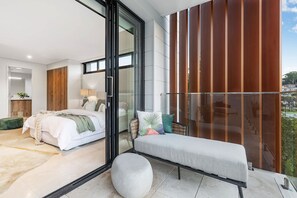Un dormitorio moderno con una cama grande, una zona de estar con cojines y un balcón con vistas.