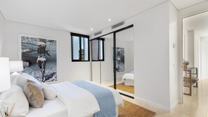 Ein modernes Schlafzimmer mit einem Bett, einem großen Spiegel und Kunstwerken an der Wand.