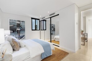 Ein modernes Schlafzimmer mit einem Bett, einem großen Spiegel und Kunstwerken an der Wand.