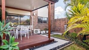 A covered patio with a wooden deck, outdoor seating, and a garden area with plants and a small water feature. - Seadream on Nelson. New listing.
Pet friendly , 300m stroll to beach and cafes.  (Woolgoolga)