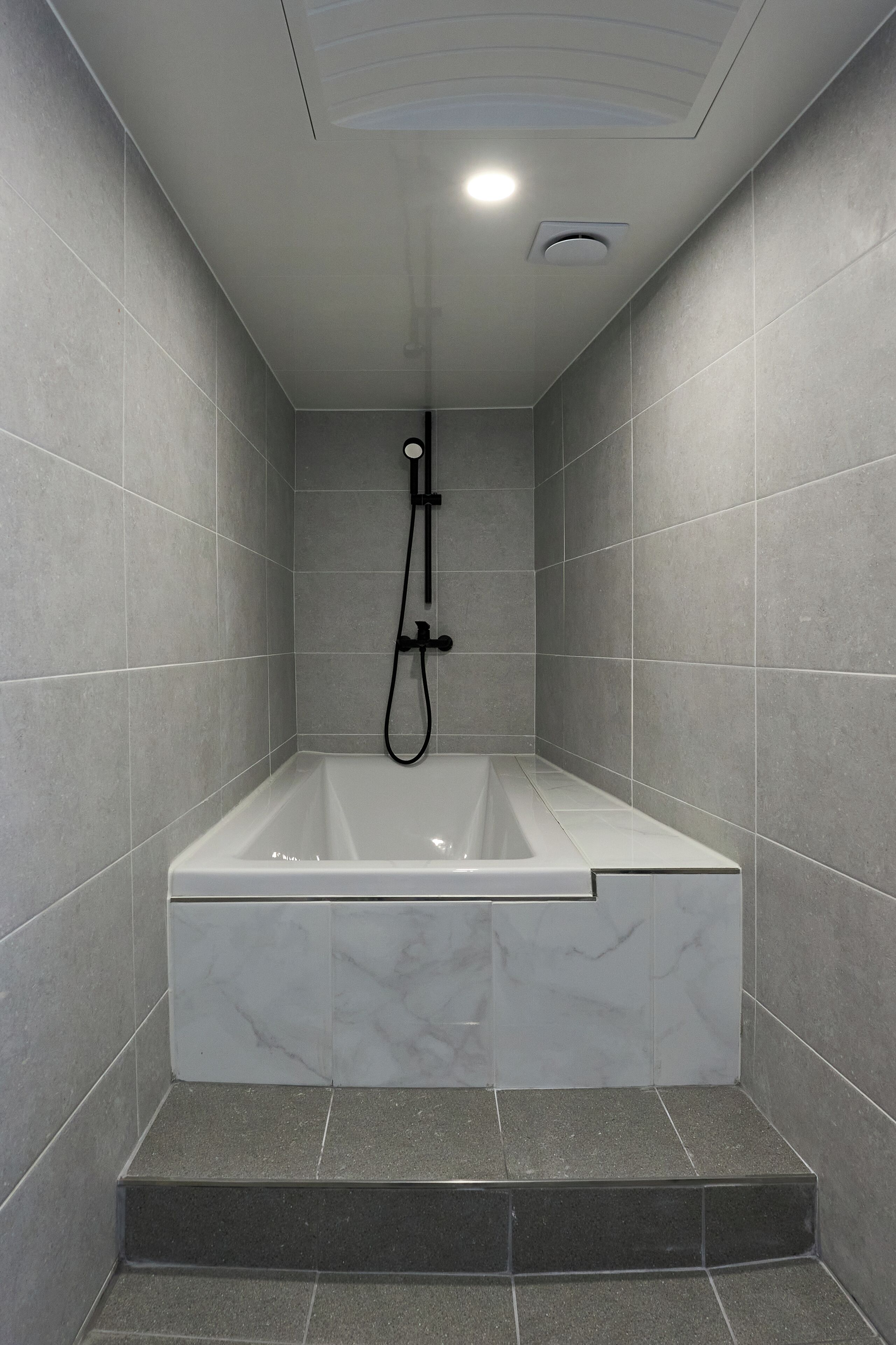 A modern bathroom with a freestanding bathtub, tiled walls, and a built-in showerhead.