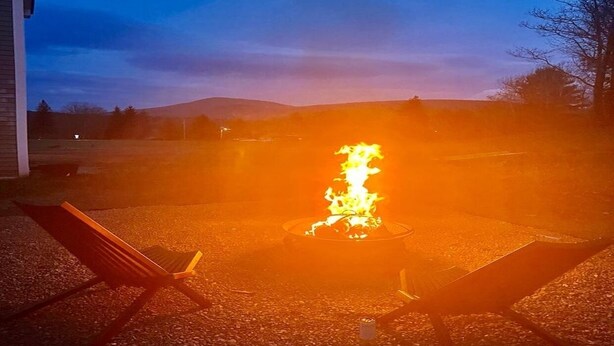 Ein Feuerkorb mit zwei Stühlen in einem Garten.